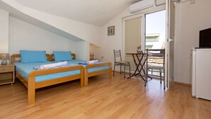 Un dormitorio con dos camas de madera, un escritorio, una silla, un espejo y un refrigerador.