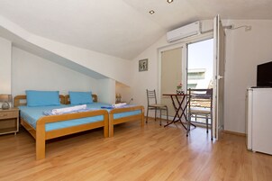 Un dormitorio con dos camas de madera, un escritorio, una silla, un espejo y un refrigerador.