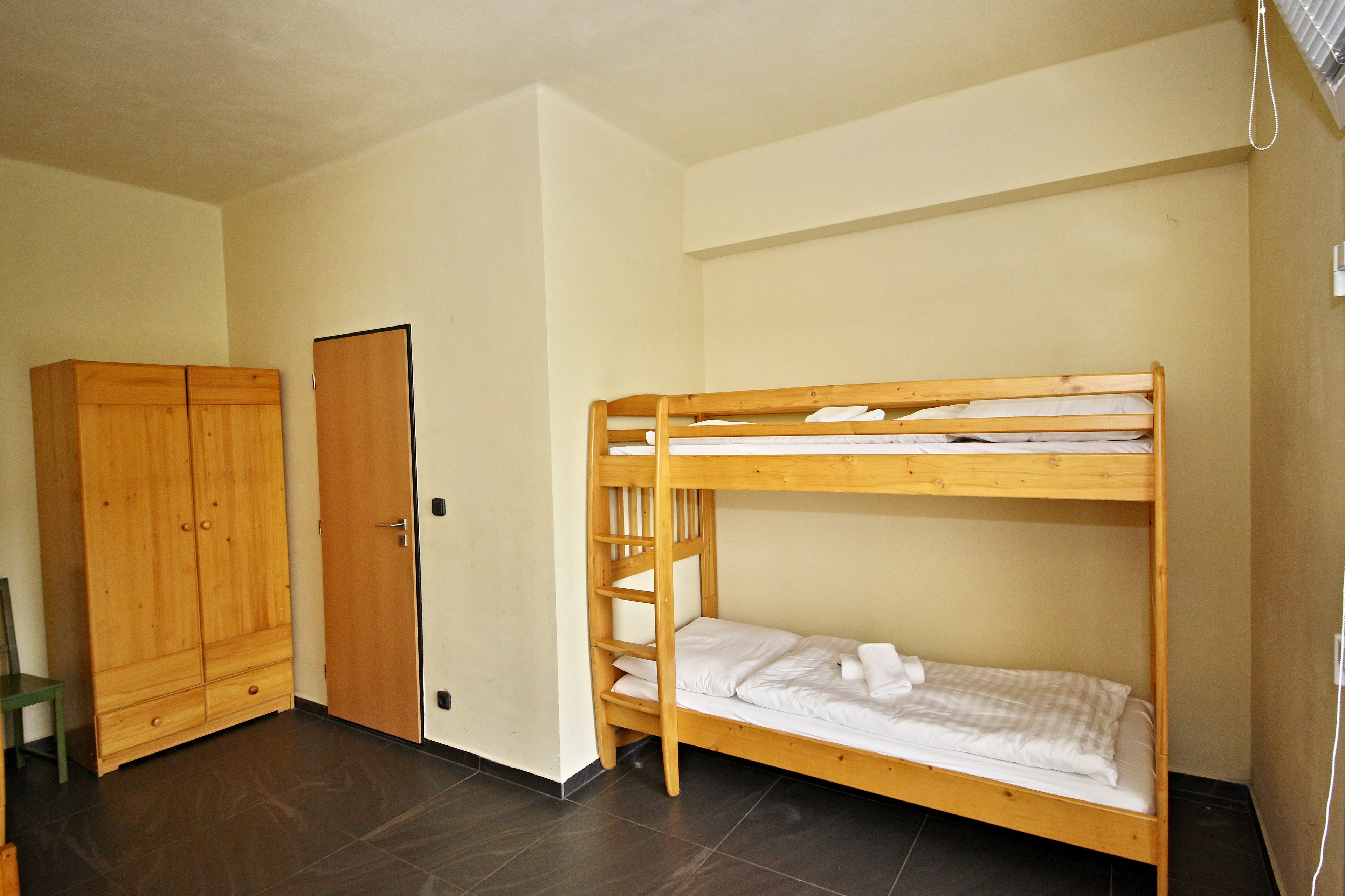Una habitación con literas, un armario de madera y una puerta.