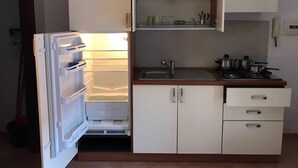 A compact kitchen with a built-in refrigerator, a sink, and a stove. - Residence Moscati (Avellino)