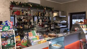 A bar area with shelves of various bottles, a display of Tic Tac gum, and a counter with food items. - Residence Moscati (Avellino)