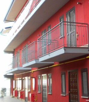 A red building with multiple balconies and windows, featuring a simple architectural design.