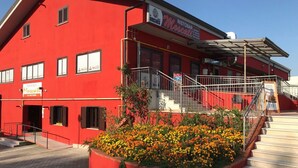 A red building with a sign for 'Ristorante Marcato' and a staircase leading to a covered area. - Residence Moscati (Avellino)