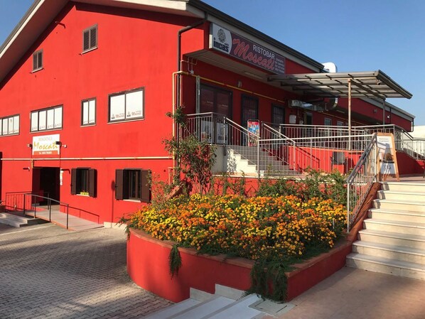 A red building with a sign for 'Ristorante Marcato' and a staircase leading to a covered area.