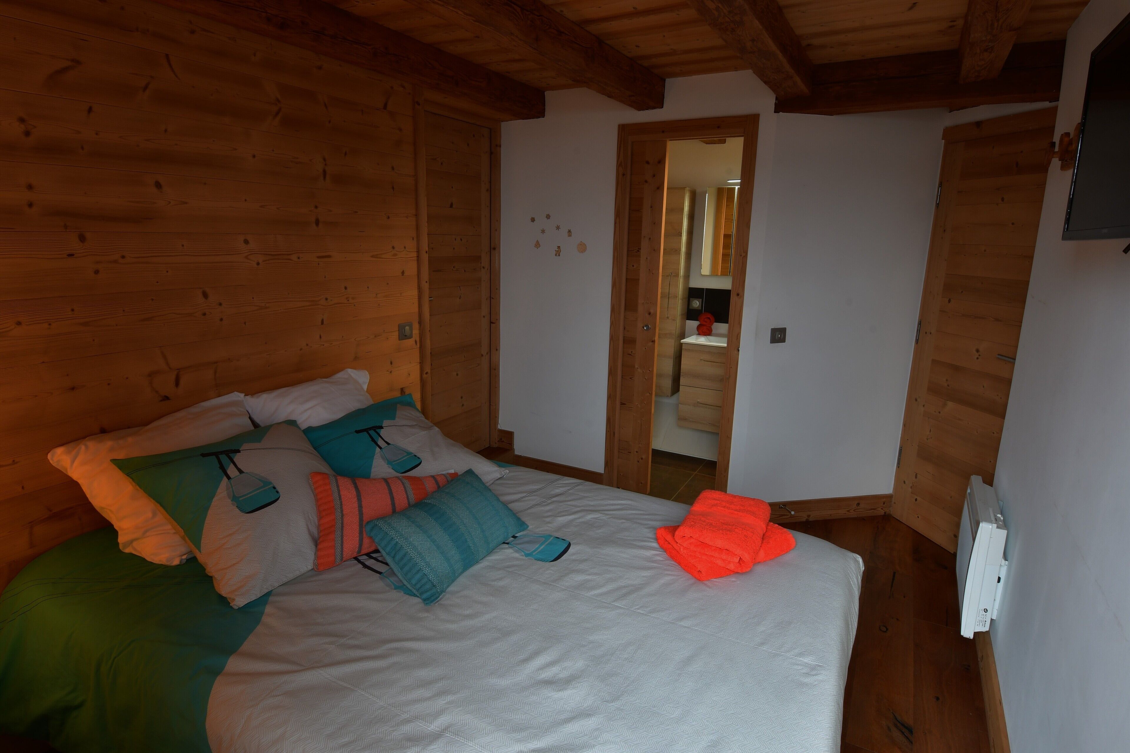 Una stanza con rivestimenti in legno, un letto, uno specchio e un termosifone.