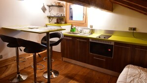 A compact kitchen with wooden cabinets, a built-in oven, and a window above the sink.