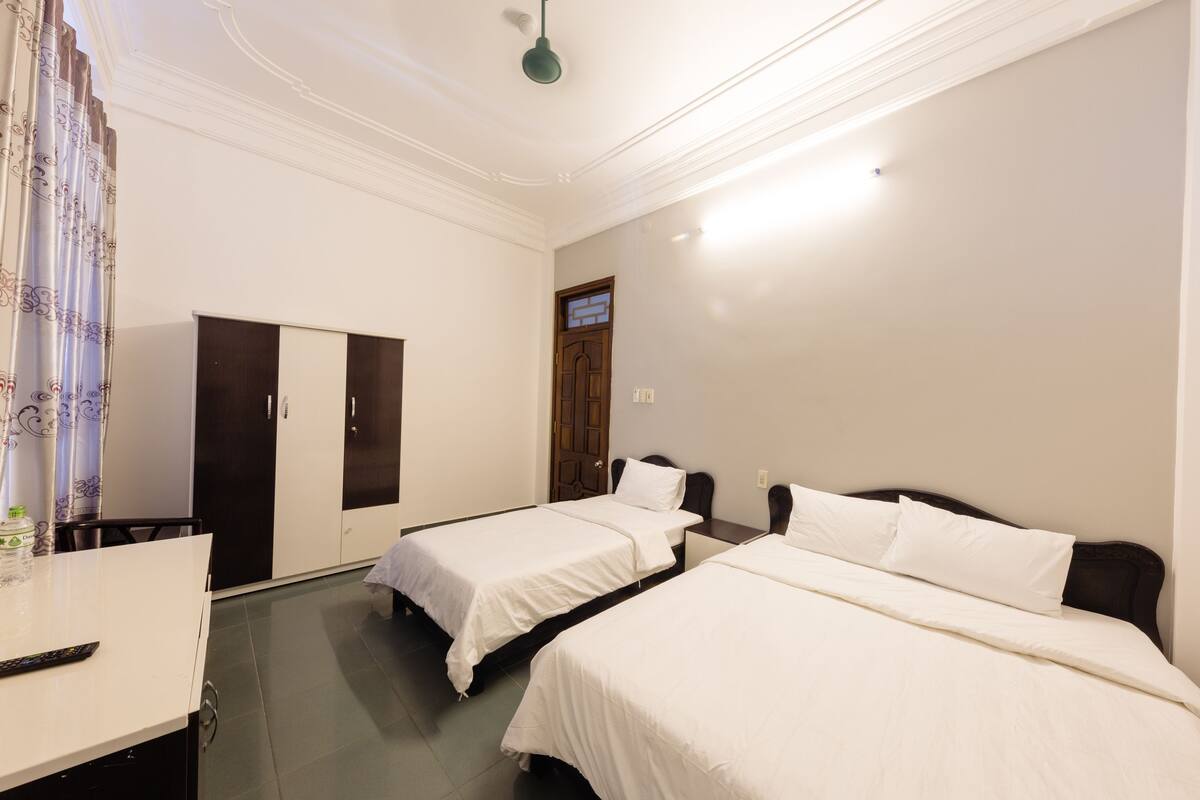 Habitación de hotel con dos camas individuales, un escritorio con silla y un armario.