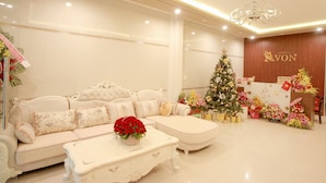 Eine luxuriöse Hotelhalle mit einem weißen Sofa, einem Couchtisch mit einer roten Blumenkomposition und einem Weihnachtsbaum.