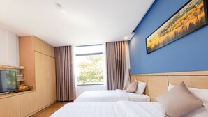 Ein Hotelzimmer mit zwei Betten, einem Fernseher, Holzschränken und einem Gemälde an der Wand.