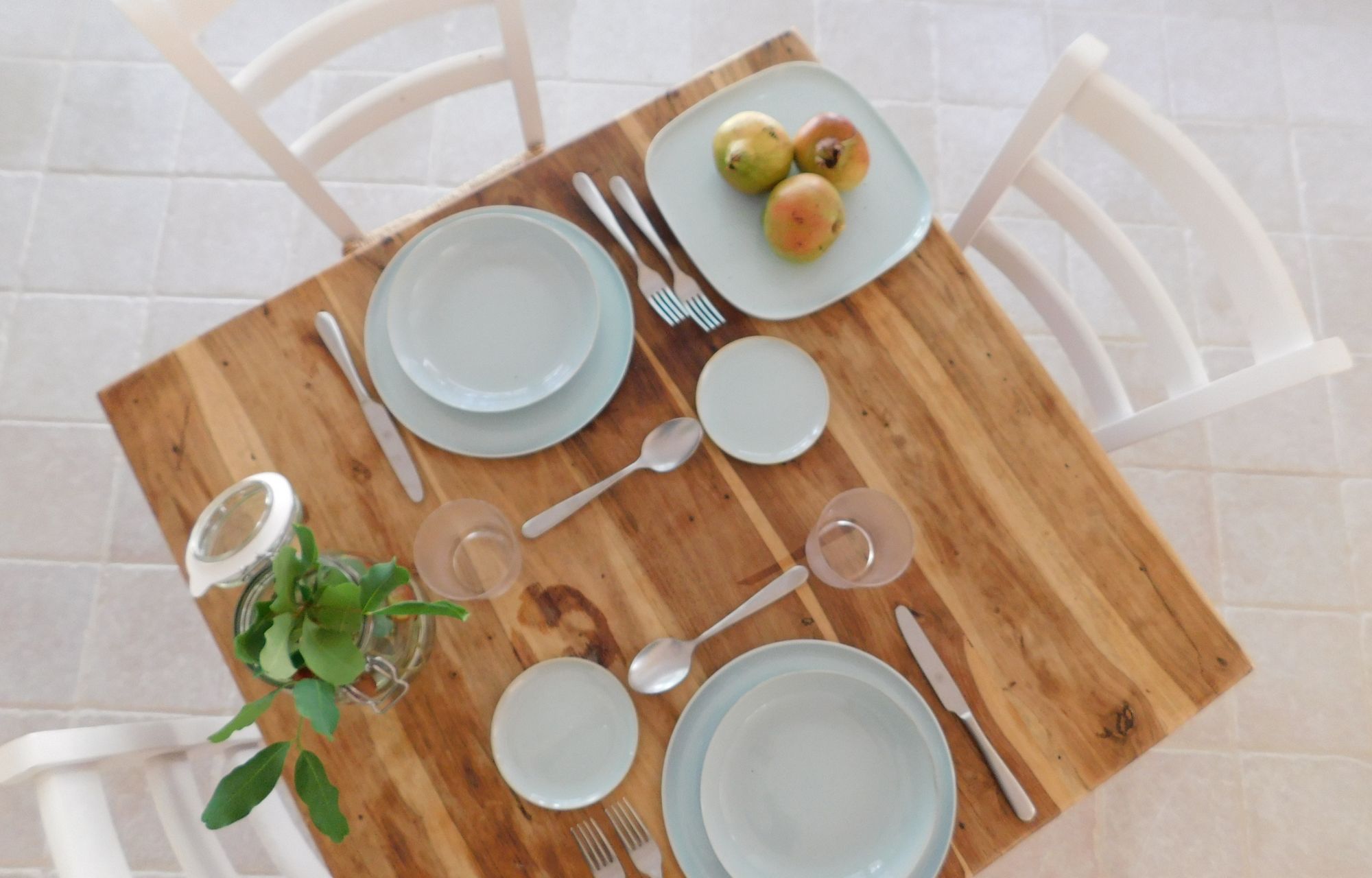 A dining table set with plates, cutlery, and a small plant.