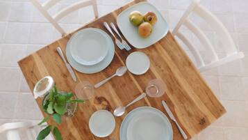 Une table à manger dressée avec des assiettes, des couverts et une petite plante.
