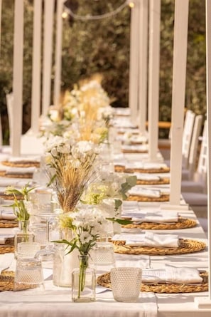 A long table set for a formal event with clear glassware and white tablecloths. - Masseria Malvindi (Mesagne)