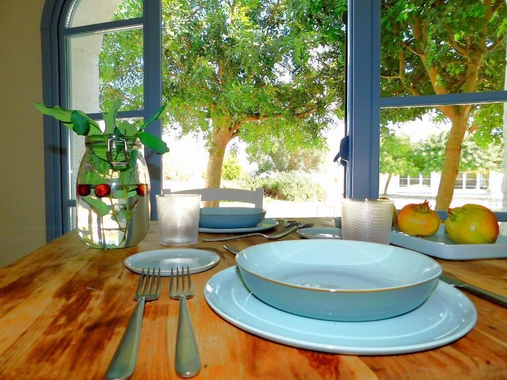Un tavolo da pranzo apparecchiato con piatti, posate e un vaso con piante verdi.
