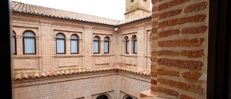 Un patio con un edificio de ladrillo, una torre y un libro abierto sobre un alféizar.