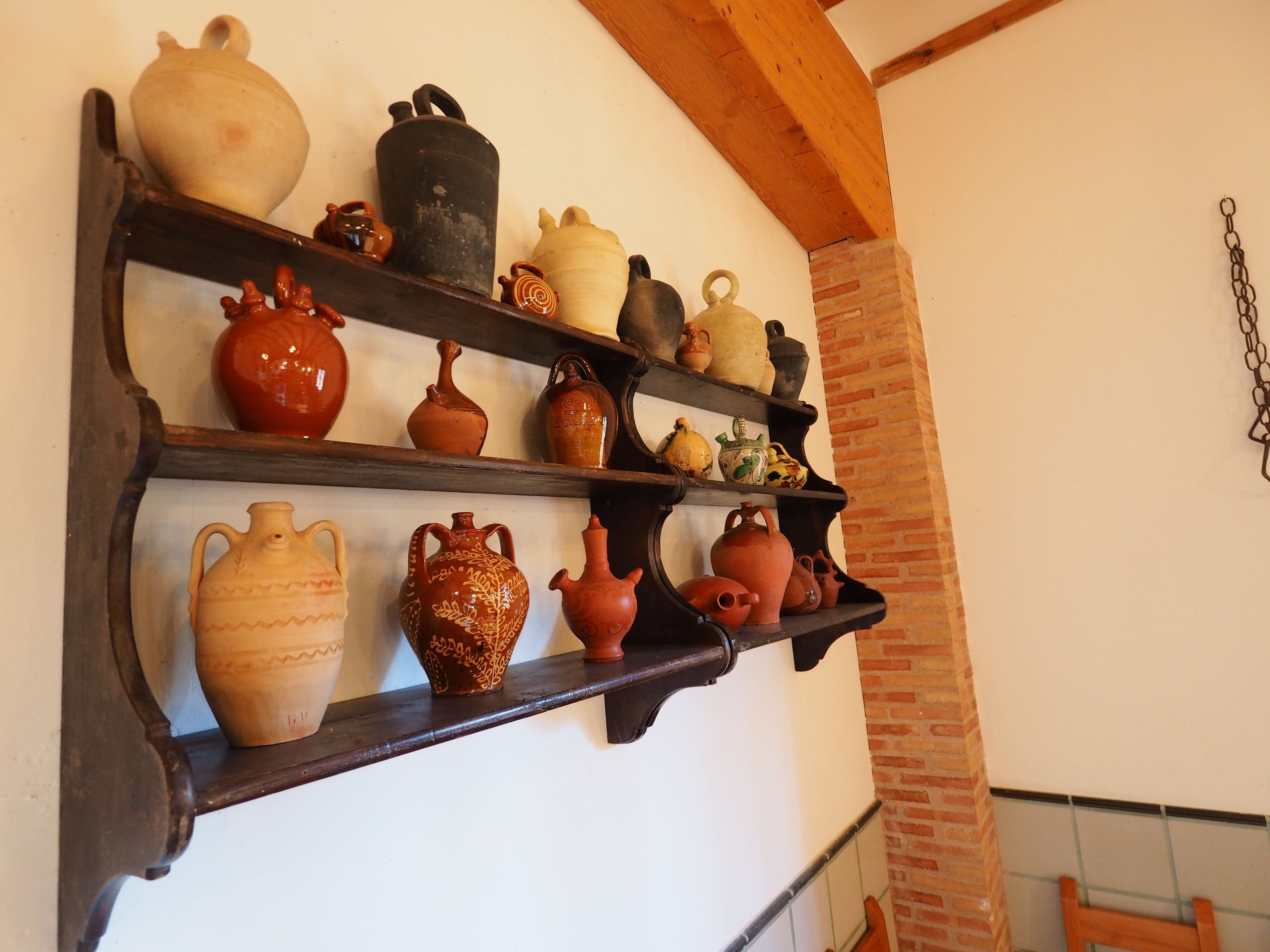 Una repisa montada en la pared con diversos floreros y macetas de cerámica.