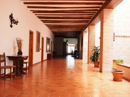 Un pasillo con vigas de madera, suelo de baldosas y plantas en macetas.