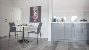 A modern kitchen with grey cabinets, a marble countertop, and a dining area with a table and chairs. - Sobe Lux (Miami Beach)