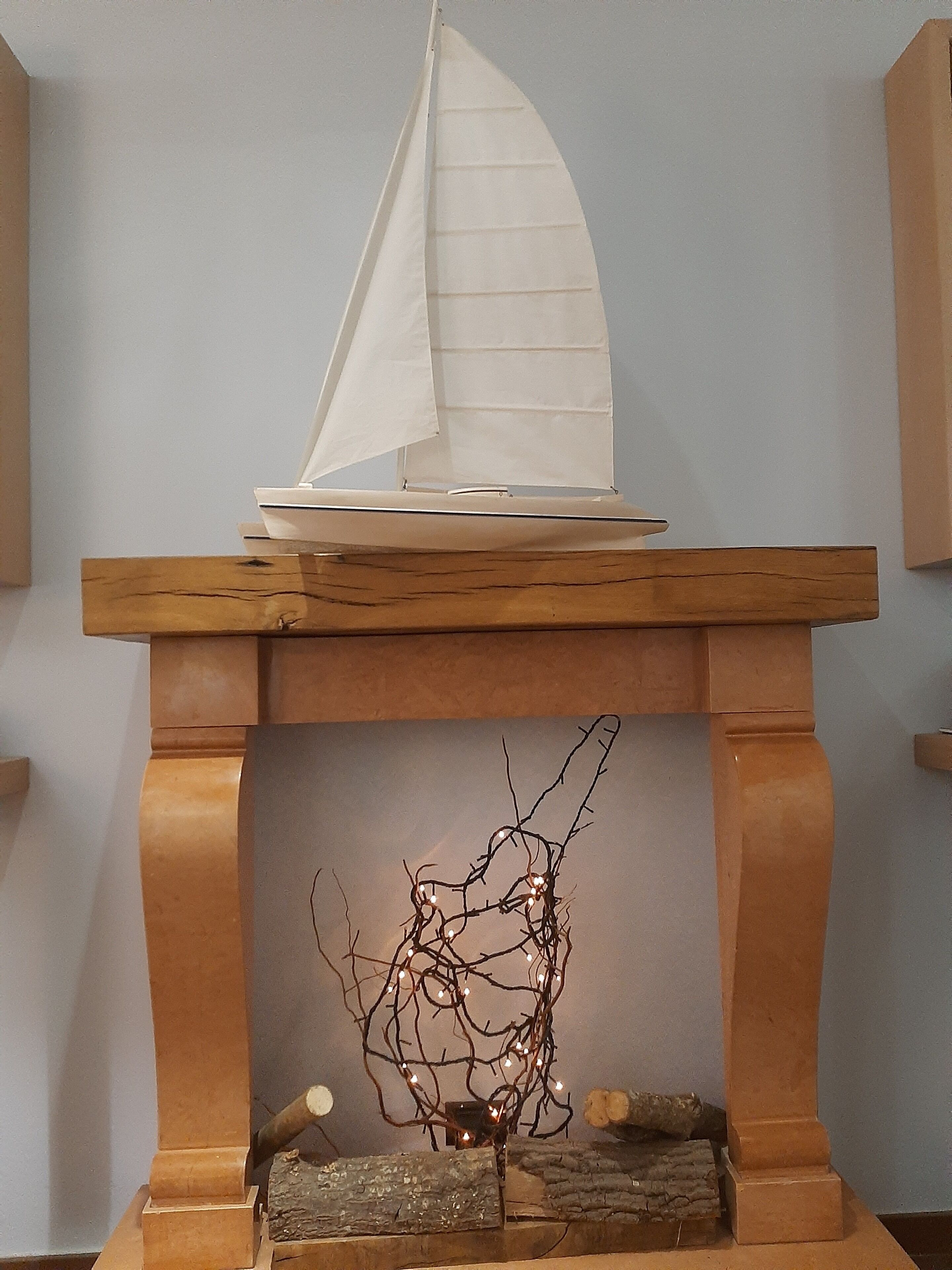 Ein Kamin mit einem dekorativen Modell eines Segelboots darauf.