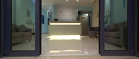 L’entrée d’un hôtel, avec un comptoir d’accueil, des canapés et une vue dégagée sur l’intérieur.