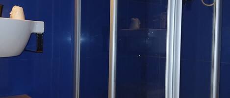 Un baño con ducha de vidrio, un lavabo blanco y un espejo en la pared.
