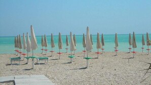 A beach with rows of beach umbrellas and chairs. - Hotel Chiaraluna (Civitanova Marche)