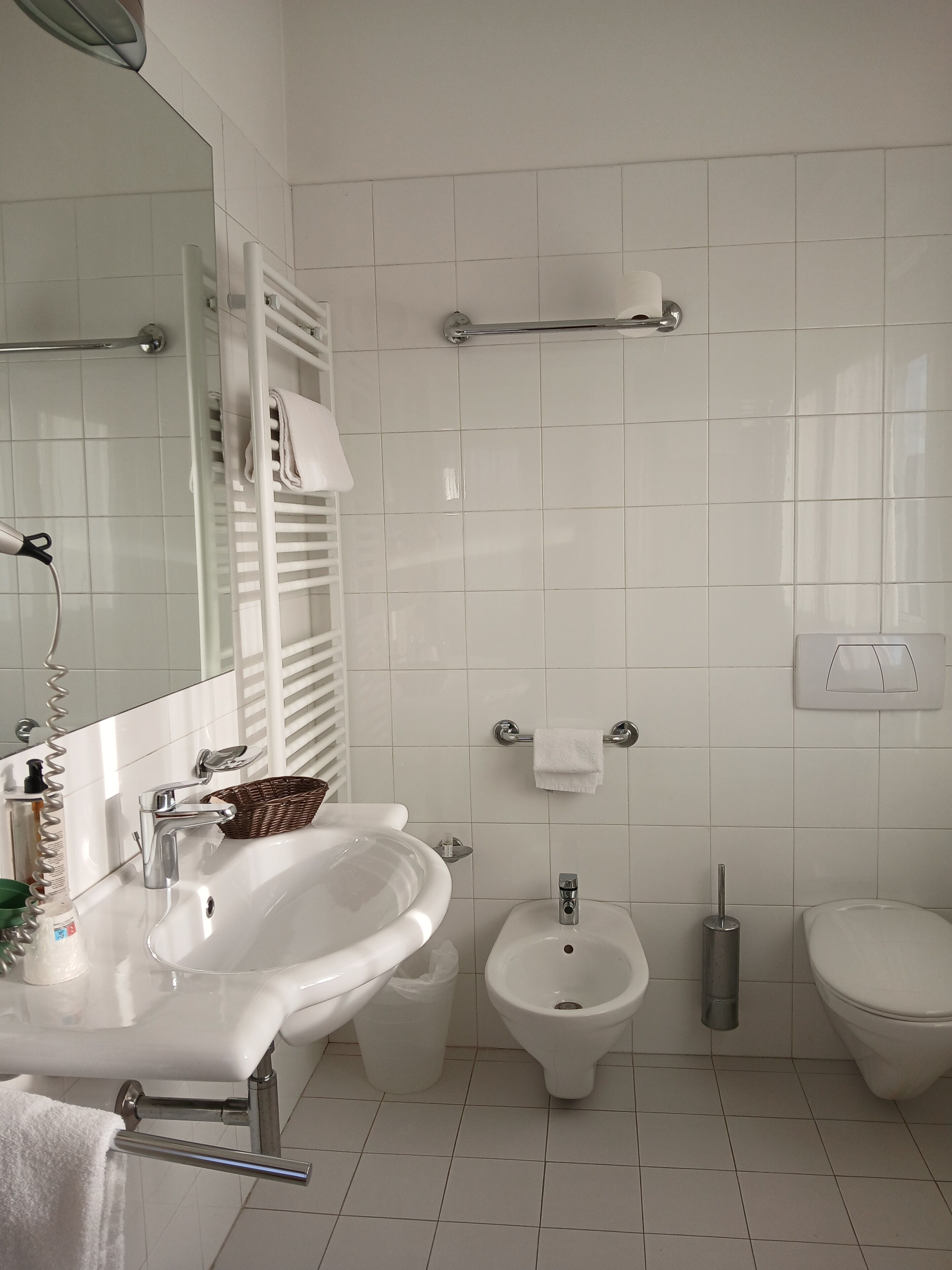 Un baño moderno con lavamanos, bidé, inodoro y espejo.