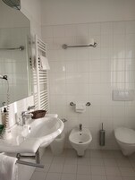 Un baño moderno con lavamanos, bidé, inodoro y espejo.