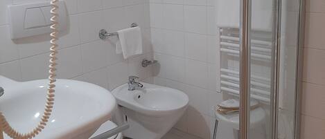 A bathroom with a toilet, bidet, and a glass shower enclosure.