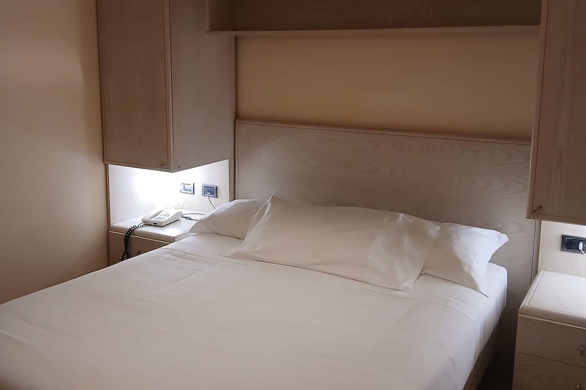 Een slaapkamer met een bed, nachtkastjes, een telefoon en een kledingkast.