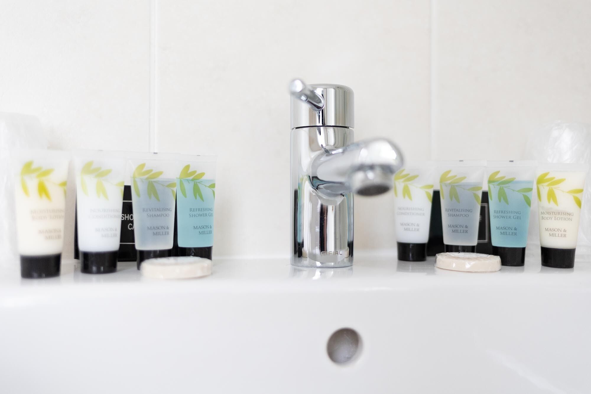 A bathroom sink with various personal care products arranged around it.