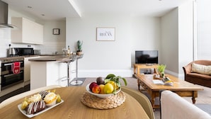 A modern kitchen with a dining area, a TV, and a cozy seating area with a plant. - Red Lea Apartments (Scarborough)