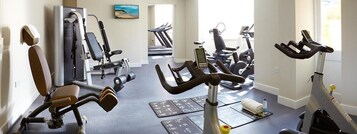 Ein Fitnessstudio mit Trainingsgeräten, Laufbändern und einem digitalen Bildschirm.