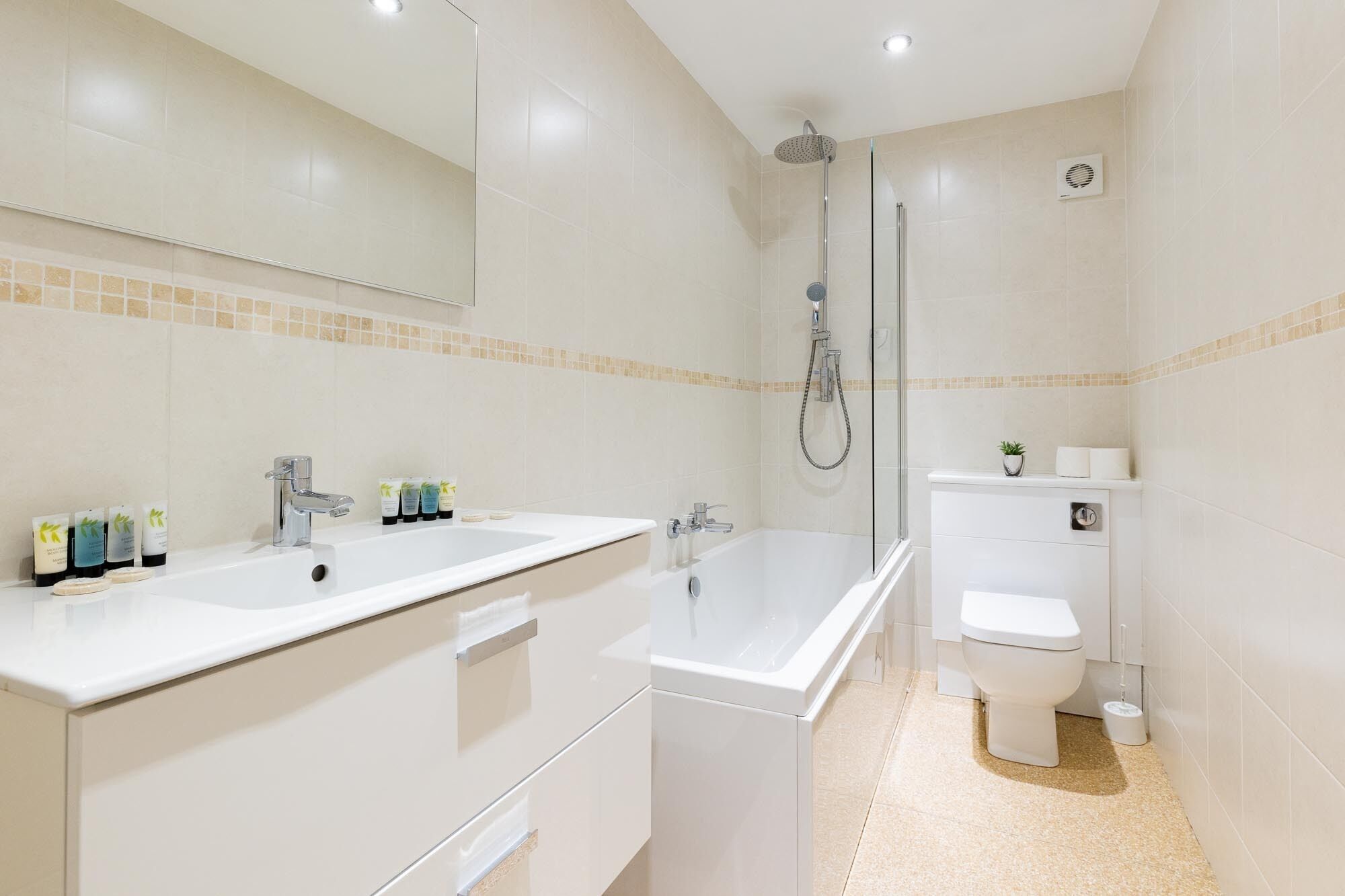 A modern bathroom with a double sink, a bathtub, a shower, and a toilet.
