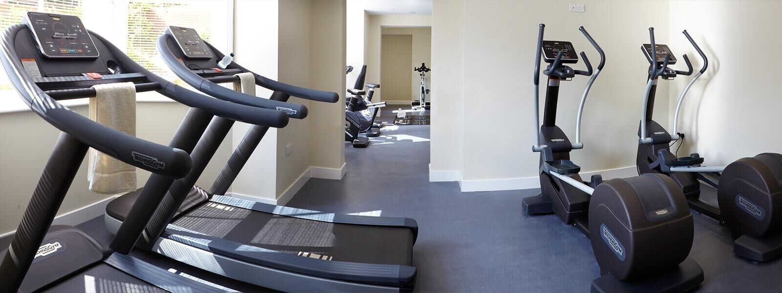Ein Fitnessstudio mit Laufbändern, Crosstrainern und Gewichtecken.
