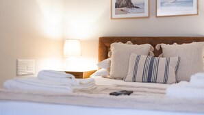 A neatly made bed with pillows and a folded towel, a bedside lamp, and two framed pictures on the wall. - Red Lea Apartments (Scarborough)