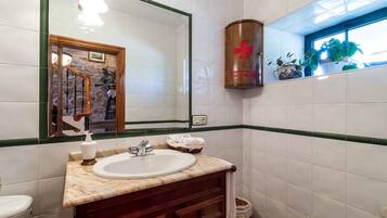 Un baño con lavamanos blanco, tocador de madera y un espejo grande.