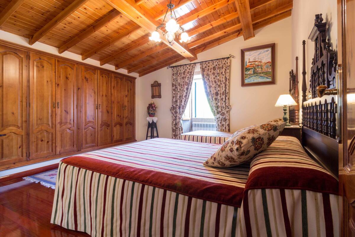 Un dormitorio con una cama grande, un armario de madera y una araña.