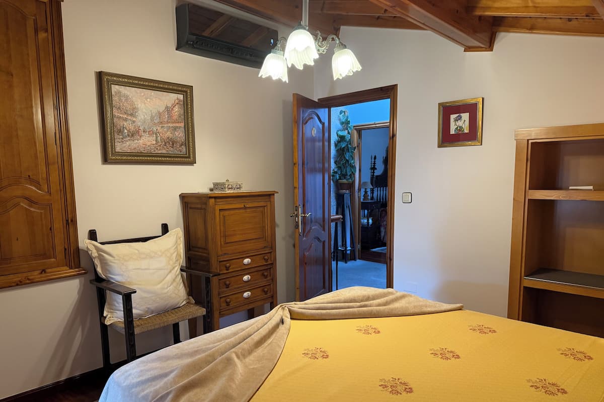 Un dormitorio con cama, cómoda de madera y una puerta que da a otra habitación.