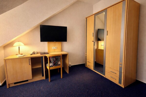A small, well-lit room with a desk, chair, and wardrobe. - Turmhotel Schwedt (Schwedt/Oder)