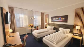 A hotel room with two beds, a desk, a chair, a TV, and a painting on the wall.