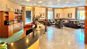 A hotel lobby with a bar area, seating, and artwork on the walls. - Turmhotel Schwedt (Schwedt/Oder)