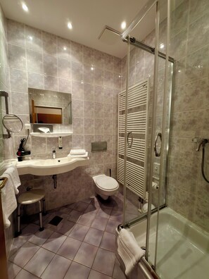 A modern bathroom with a glass-enclosed shower, a sink with a mirror, and a toilet. - Turmhotel Schwedt (Schwedt/Oder)