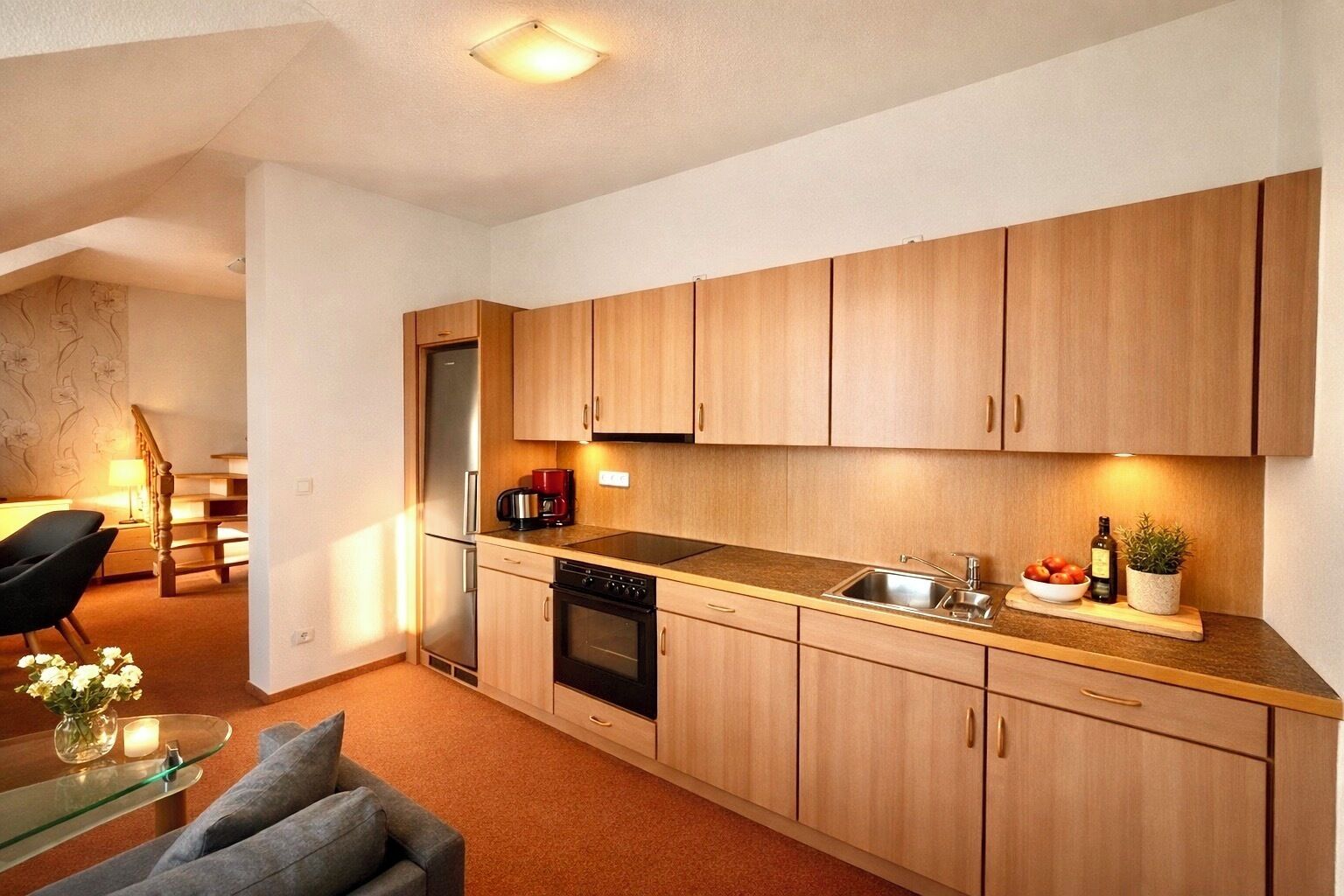 Una cocina compacta con armarios de madera, horno empotrado y cafetera.