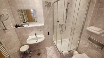 A modern bathroom with a glass-enclosed shower, a sink, a toilet, and a mirror.