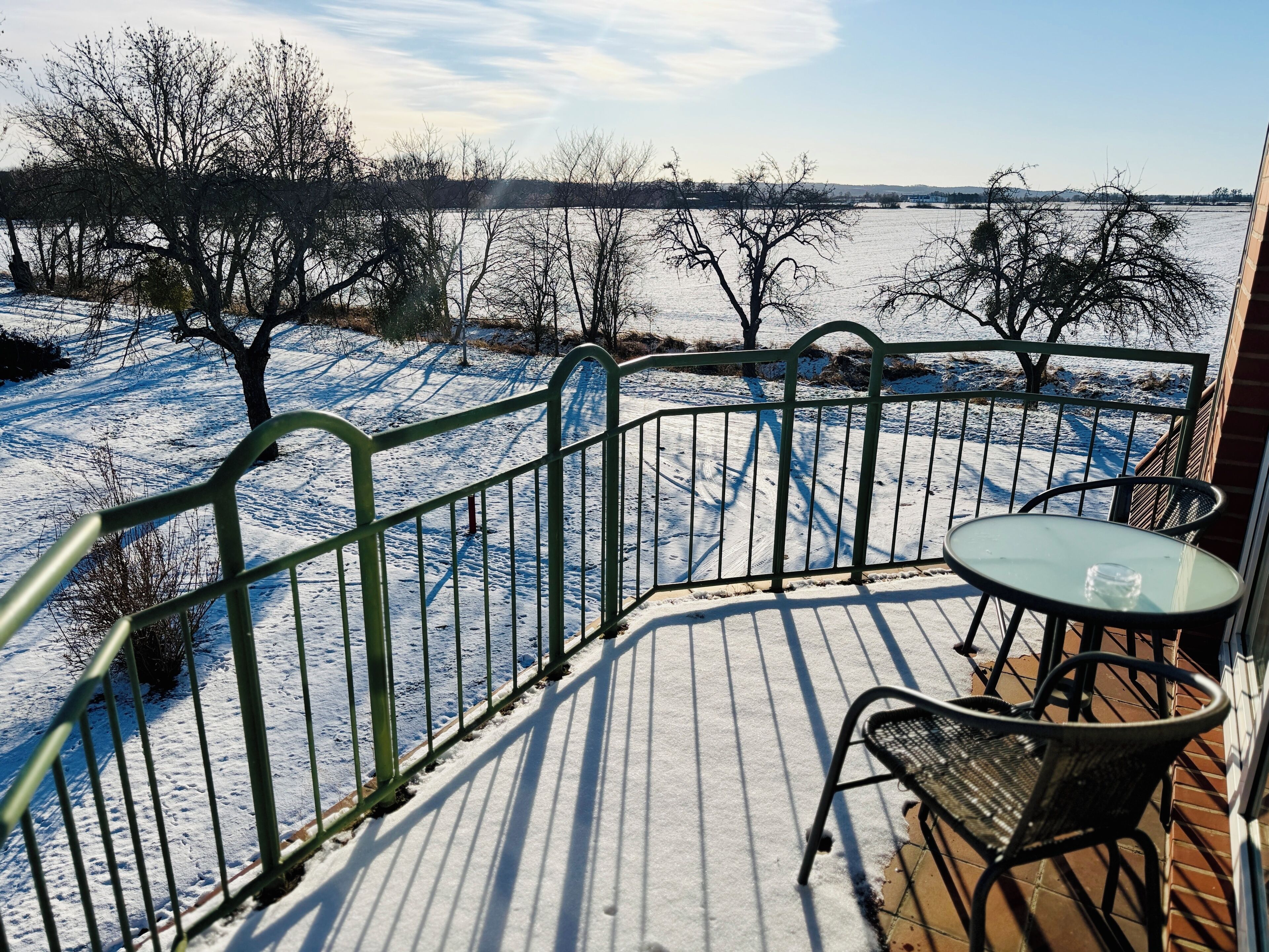 Eine Terrasse mit Metallgeländer, einem Glastisch und einem Stuhl.