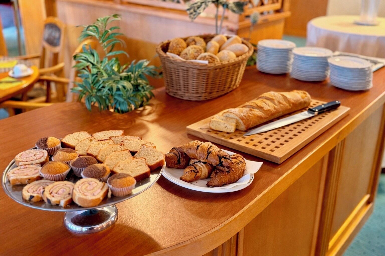A buffet table with various baked goods, including bread, muffins, and pastries.
