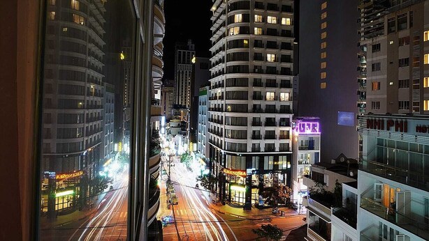 Vista noturna de um horizonte urbano com edifícios modernos, incluindo um hotel chamado 'LegendSea' com sinalização iluminada.