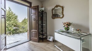 Une pièce avec un bureau en verre, un miroir et une vue sur un balcon aménagé avec du mobilier d’extérieur.