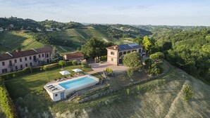 Une villa dotée d’une piscine, de panneaux solaires et, en arrière-plan, de vignes cultivées en terrasses.