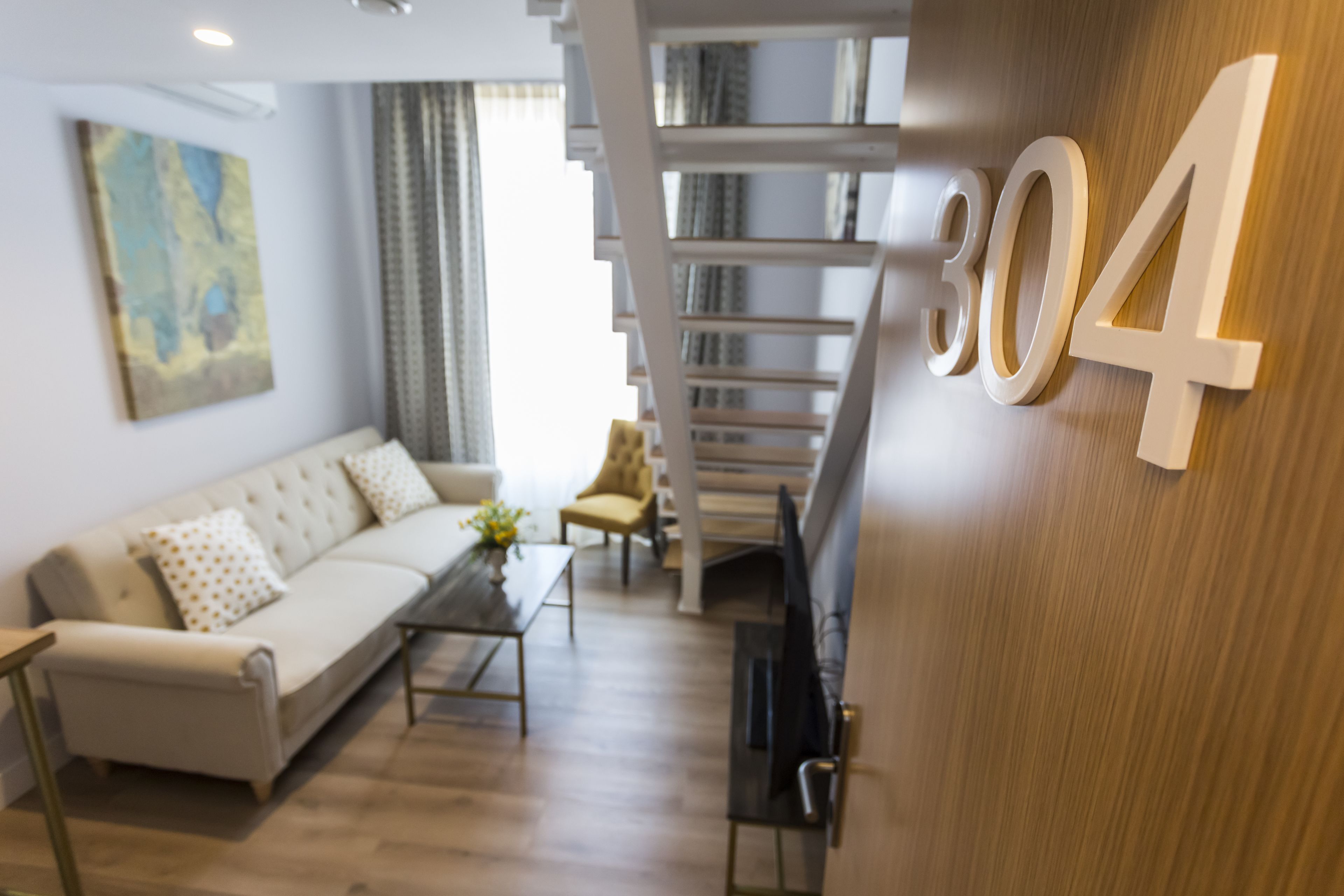Un salon moderne avec un canapé, une table basse et un escalier menant à un niveau supérieur.